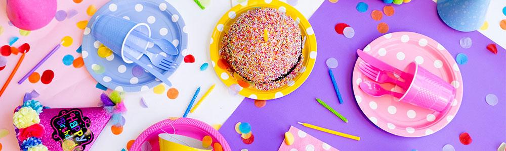 A pink and purple image of various birthday party things such as cake, hats, and confetti